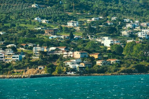 Free Idyllic hillside residential area with lush greenery by the coastline. Stock Photo