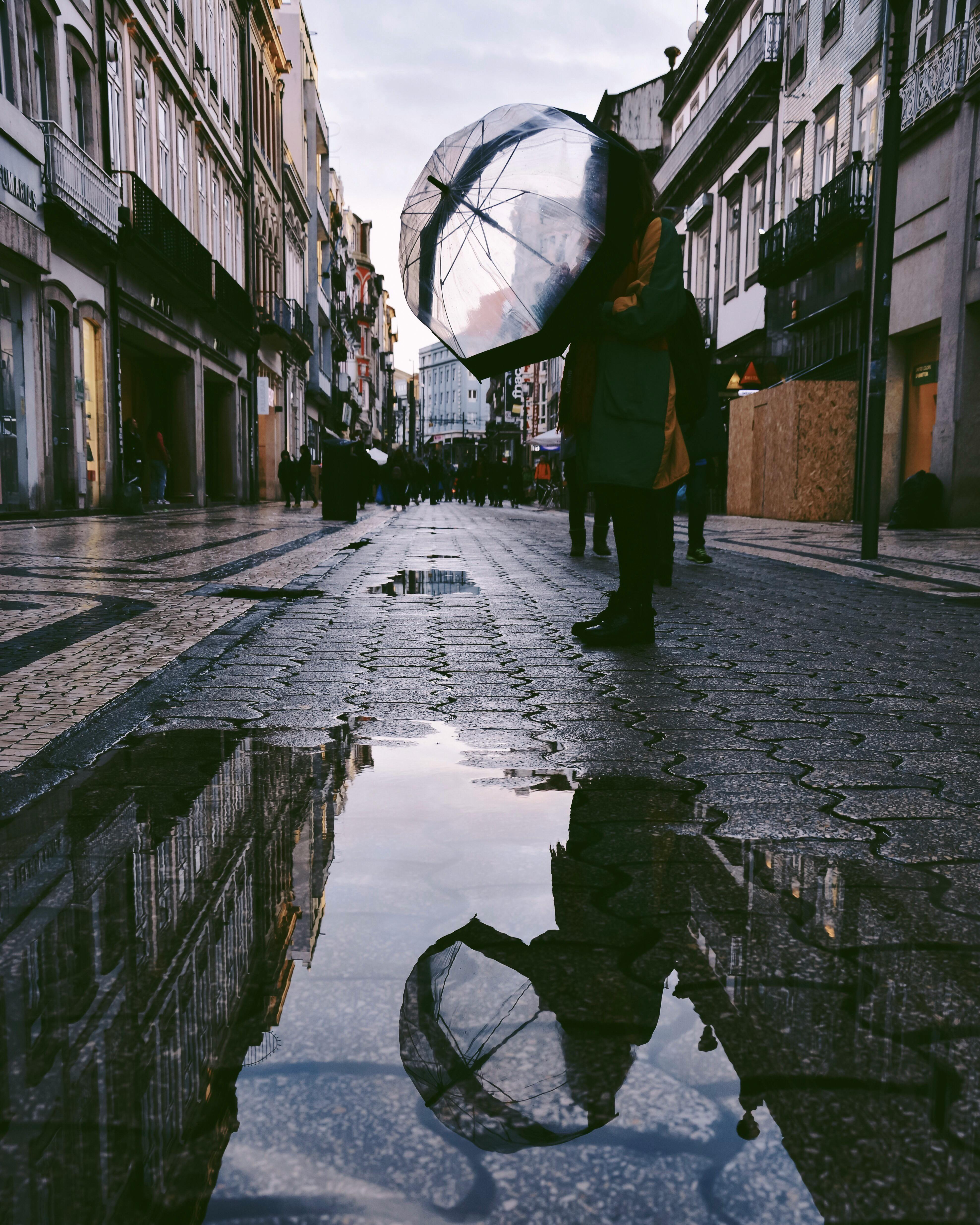 person standing on street near puddle