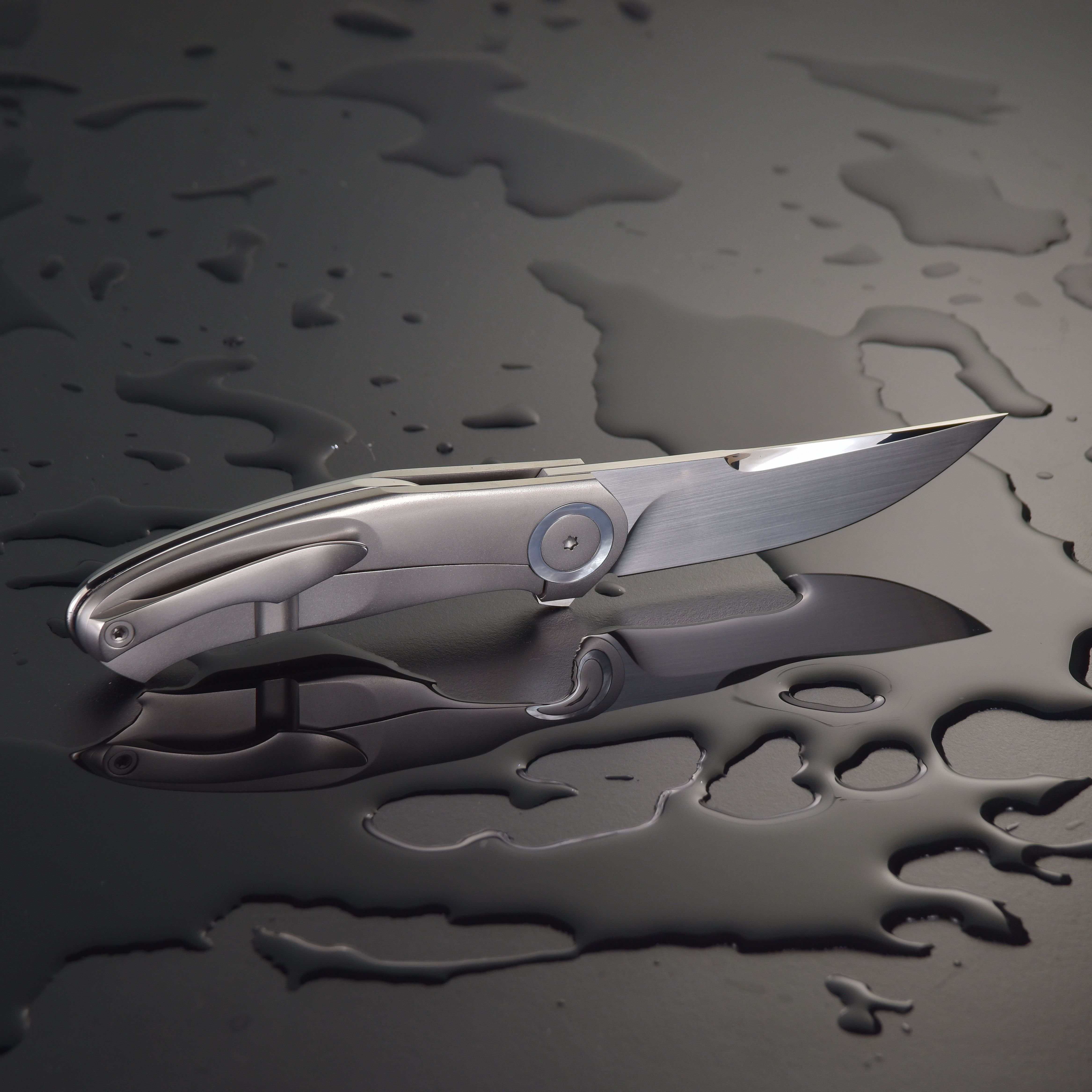Close-up of a sleek pocket knife on a wet surface, showcasing sharpness and stainless steel design.