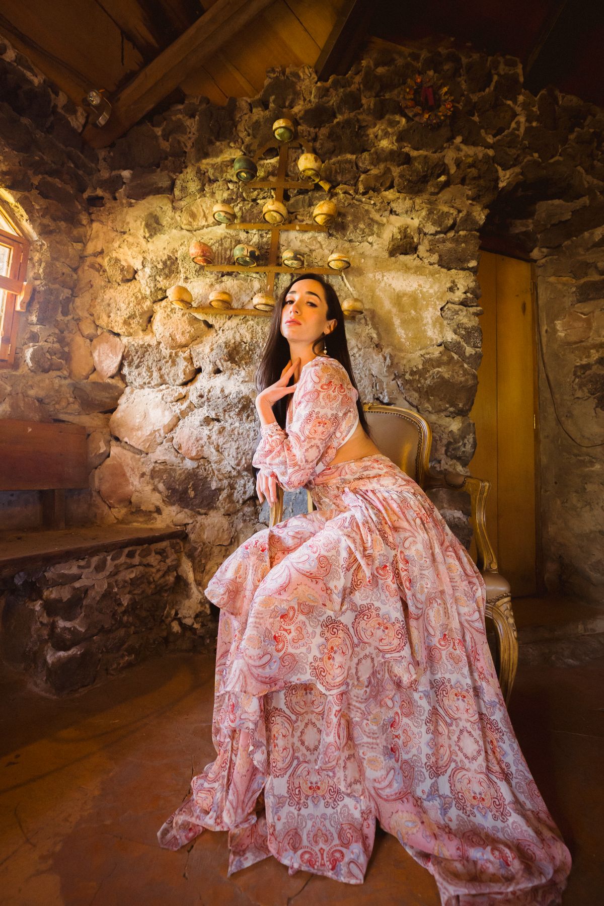 A woman in a floral boho dress sitting in a heritage interior