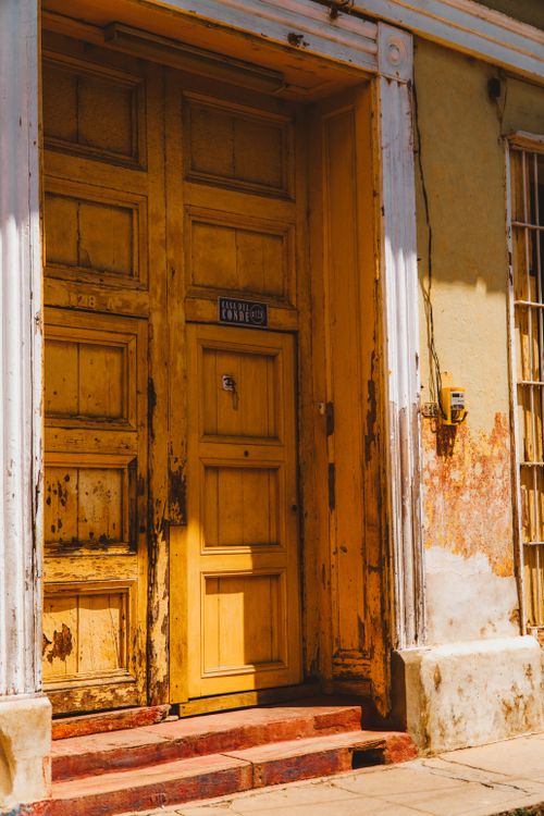 Free Weathered yellow door in a colonial facade in Trinidad, Cuba, highlighted by sunlight. Stock Photo