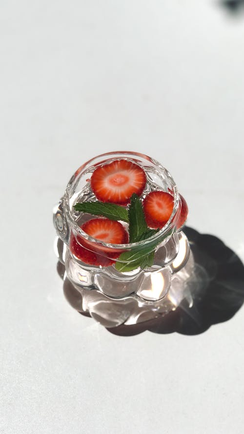 A glass of water with strawberries and mint leaves