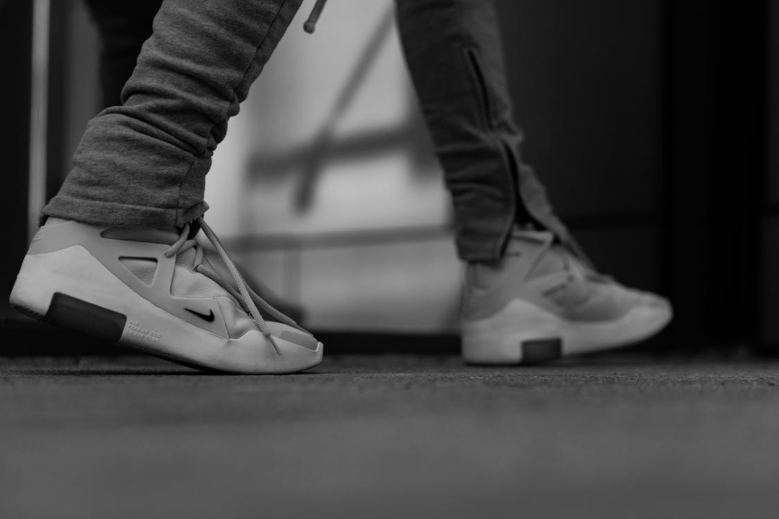 Grayscale Photography Of Person In White Nike Sneakers