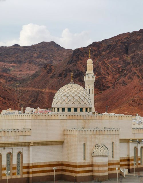 A mosque in the middle of a desert with mountains in the background