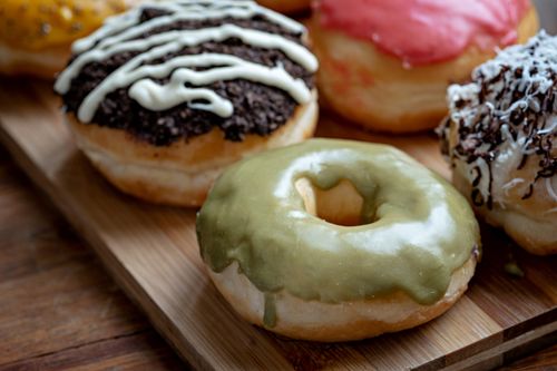 Free Close-up of colorful, delicious gourmet doughnuts with a variety of toppings and glazes on a wooden board. Stock Photo