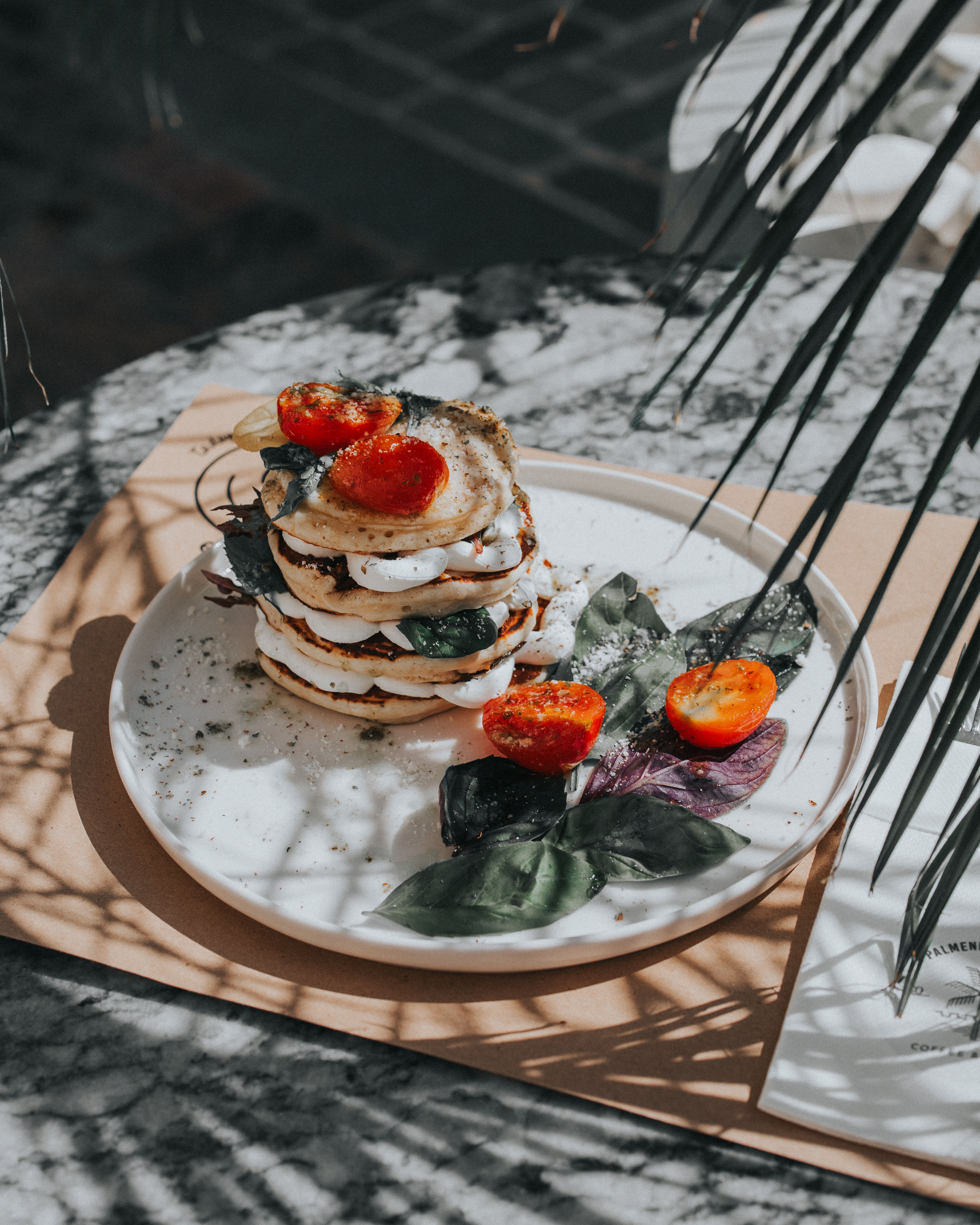 Delicious pancake stack with cheese, basil, and cherry tomatoes beautifully plated.
