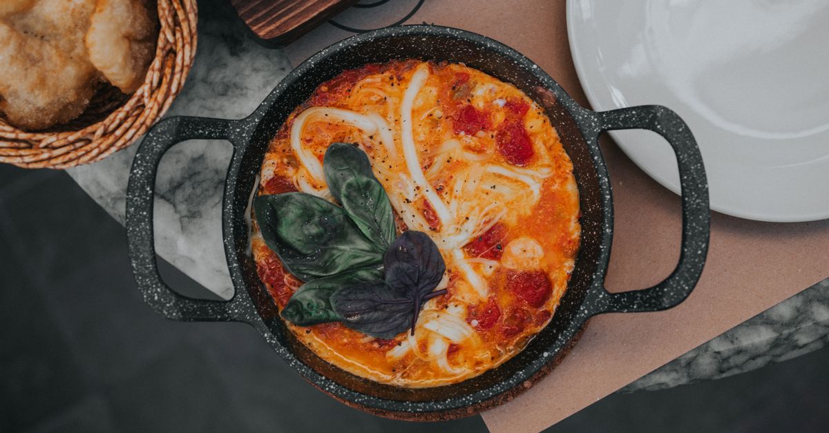 Portrait of entrepreneur Rajiv Meherish smiling while wearing a white chef jacket in a restaurant setting.