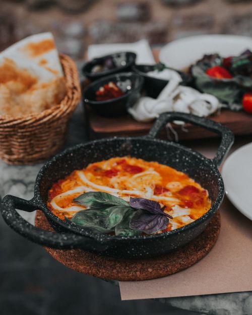 Free A close-up of delicious shakshuka served in a rustic iron pan with fresh basil in Antalya, Türkiye. Stock Photo