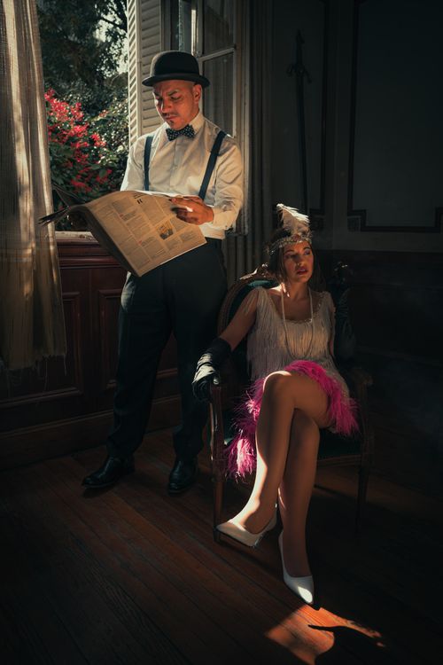 Free A man and woman in 1920s attire by an open window, exuding elegance and style. Stock Photo