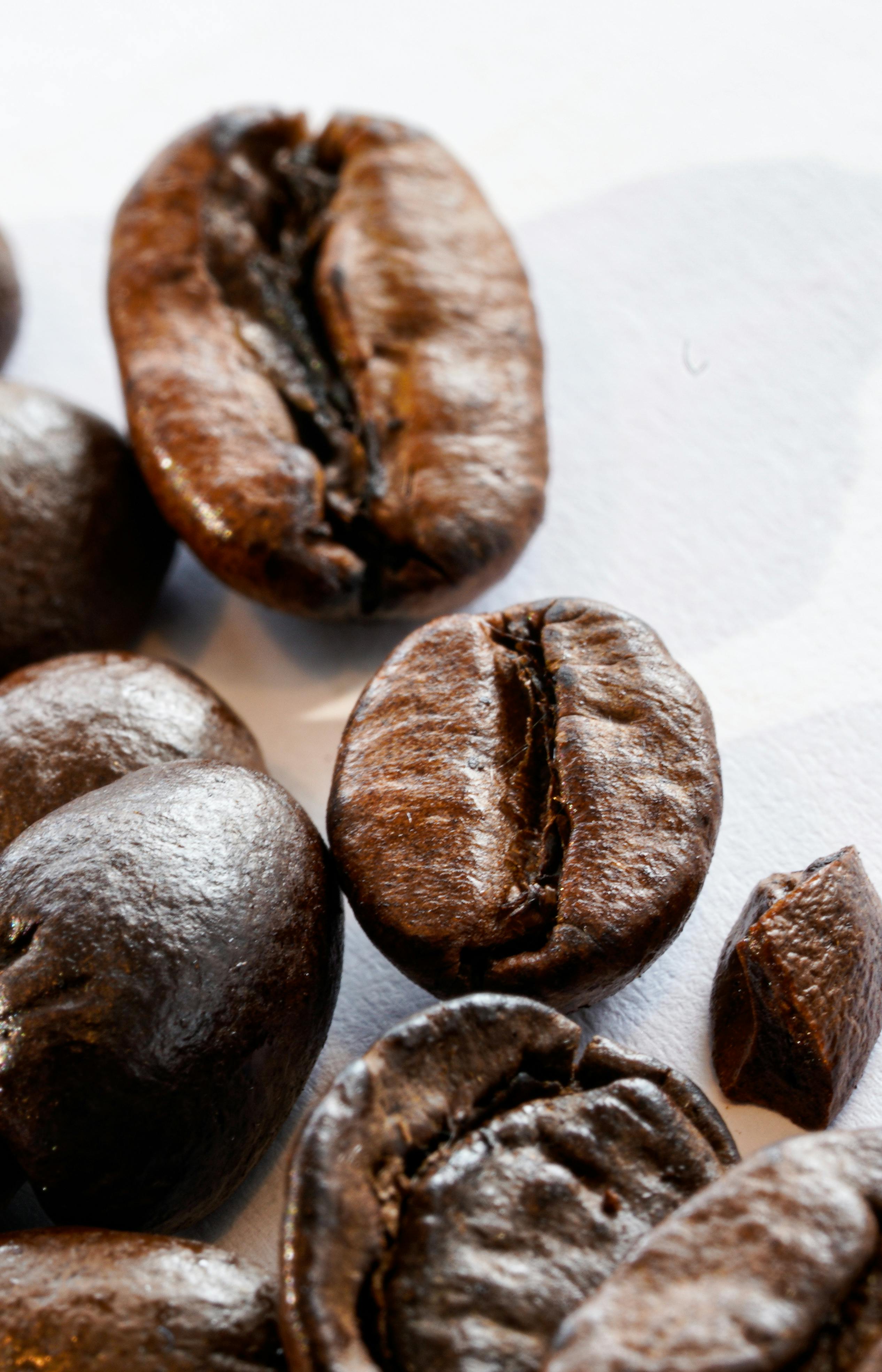Detailed shot of roasted coffee beans on a white surface, showcasing texture and color.