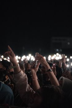 Vibrant concert crowd holding up smartphones with lights during a night performance.