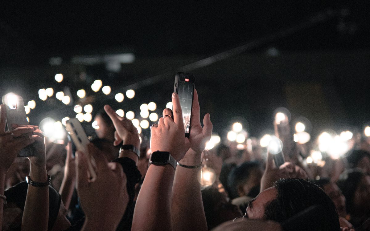 Público levantando el teléfono con la linterna encendida durante un concierto
