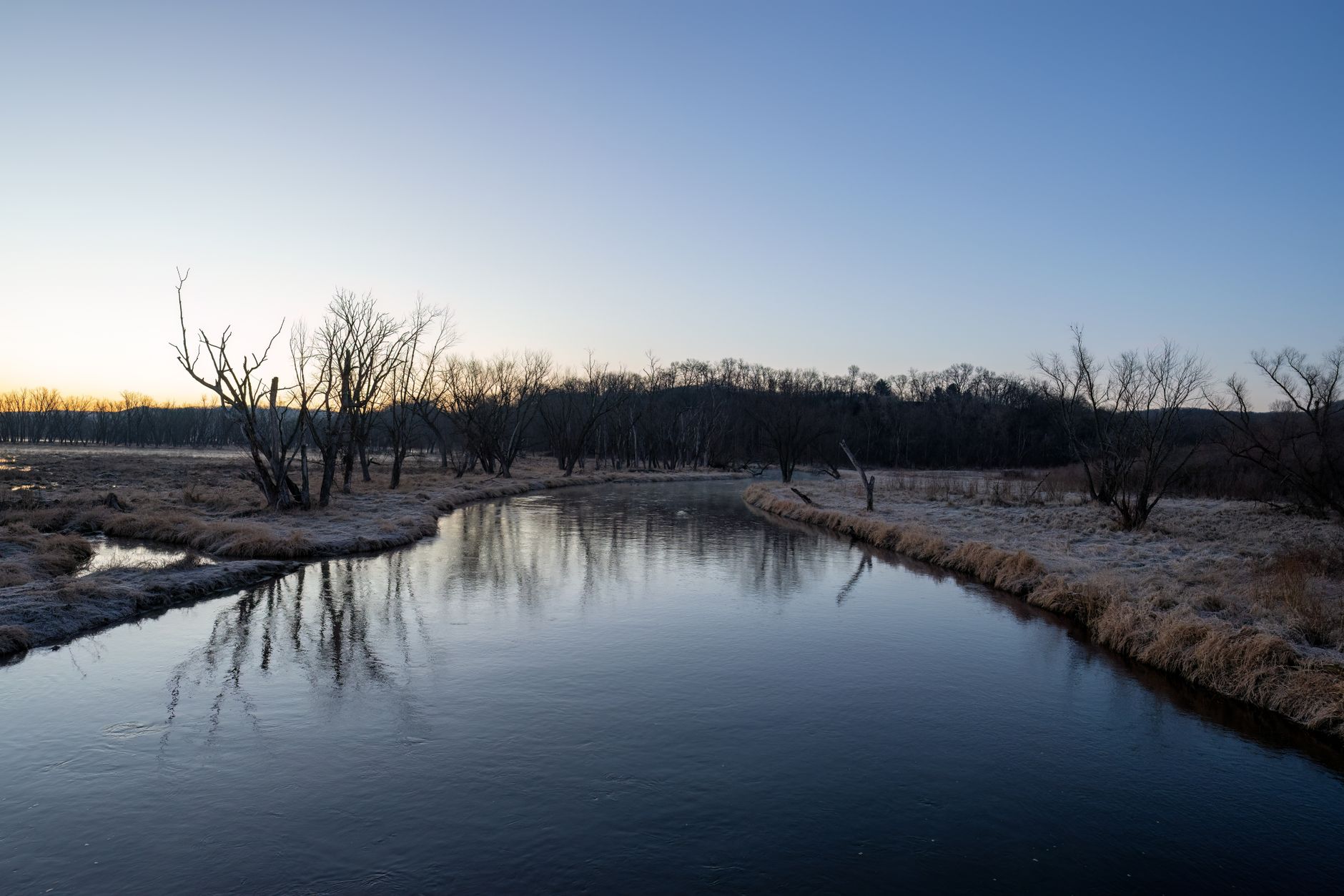 A tranquil river scene with frosty banks under a dawn sky in Tell, WI.