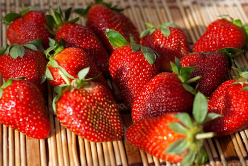 Free Close-up of ripe red strawberries on a bamboo mat, emphasizing freshness and natural nutrition. Stock Photo
