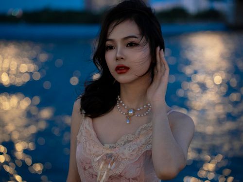 Free Portrait of an elegant woman at night with a bokeh water background. Stock Photo