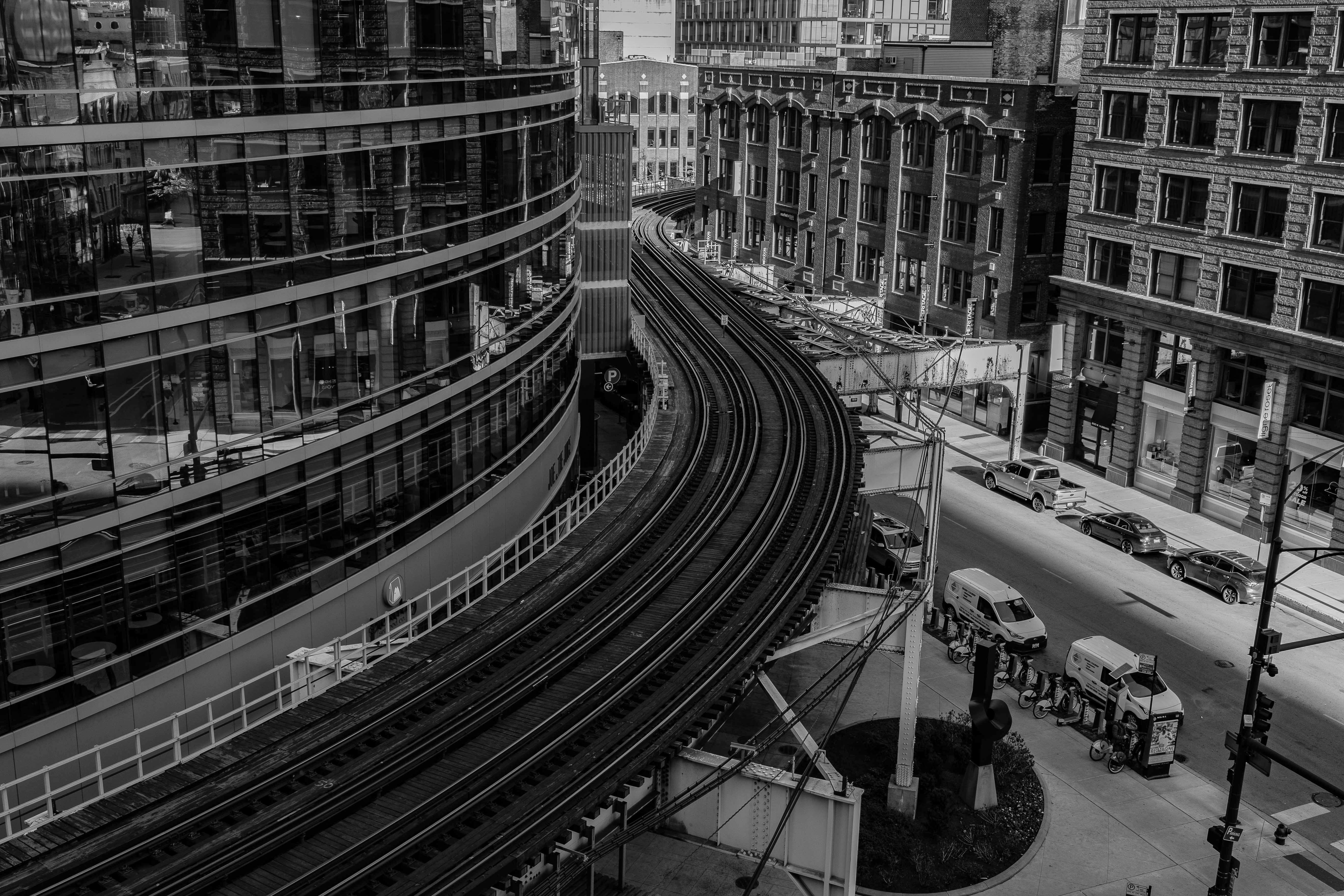 Black and white aerial photo of Chicago's urban landscape with a distinctive curved railway and surrounding architecture.