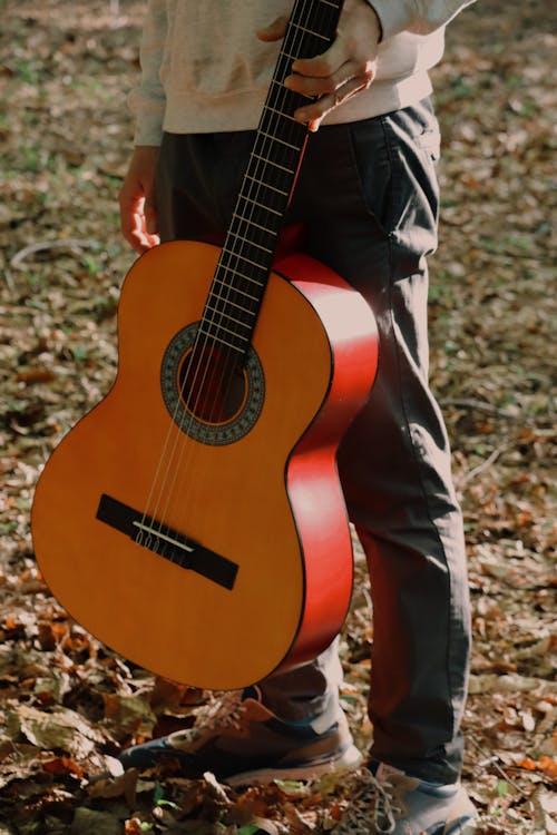 A person holding a guitar in the woods