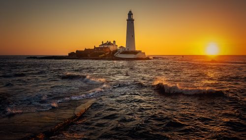 Free Golden sunset over St Mary's Lighthouse in Whitley Bay, creating a stunning coastal seascape. Stock Photo