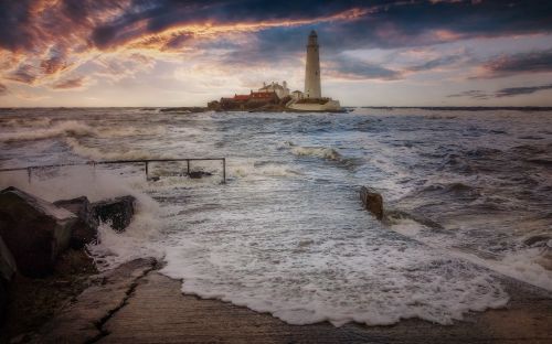 Free A calm sea view with a lighthouse at sunset, evoking tranquility and guidance. Stock Photo