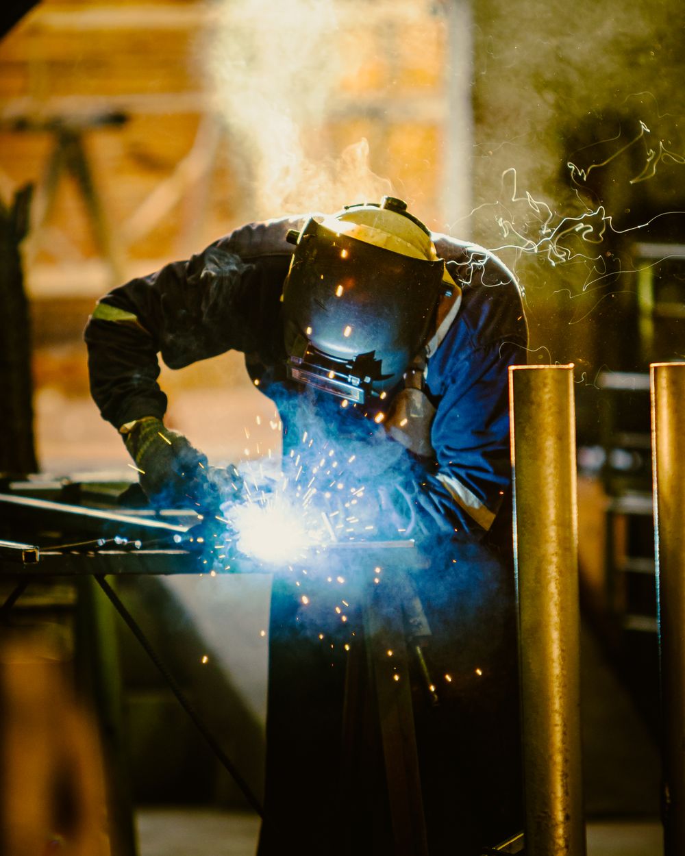 Welder bent over a bench in glowing smoke
