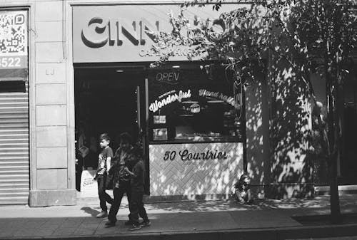 A black and white photo of two people walking past a restaurant