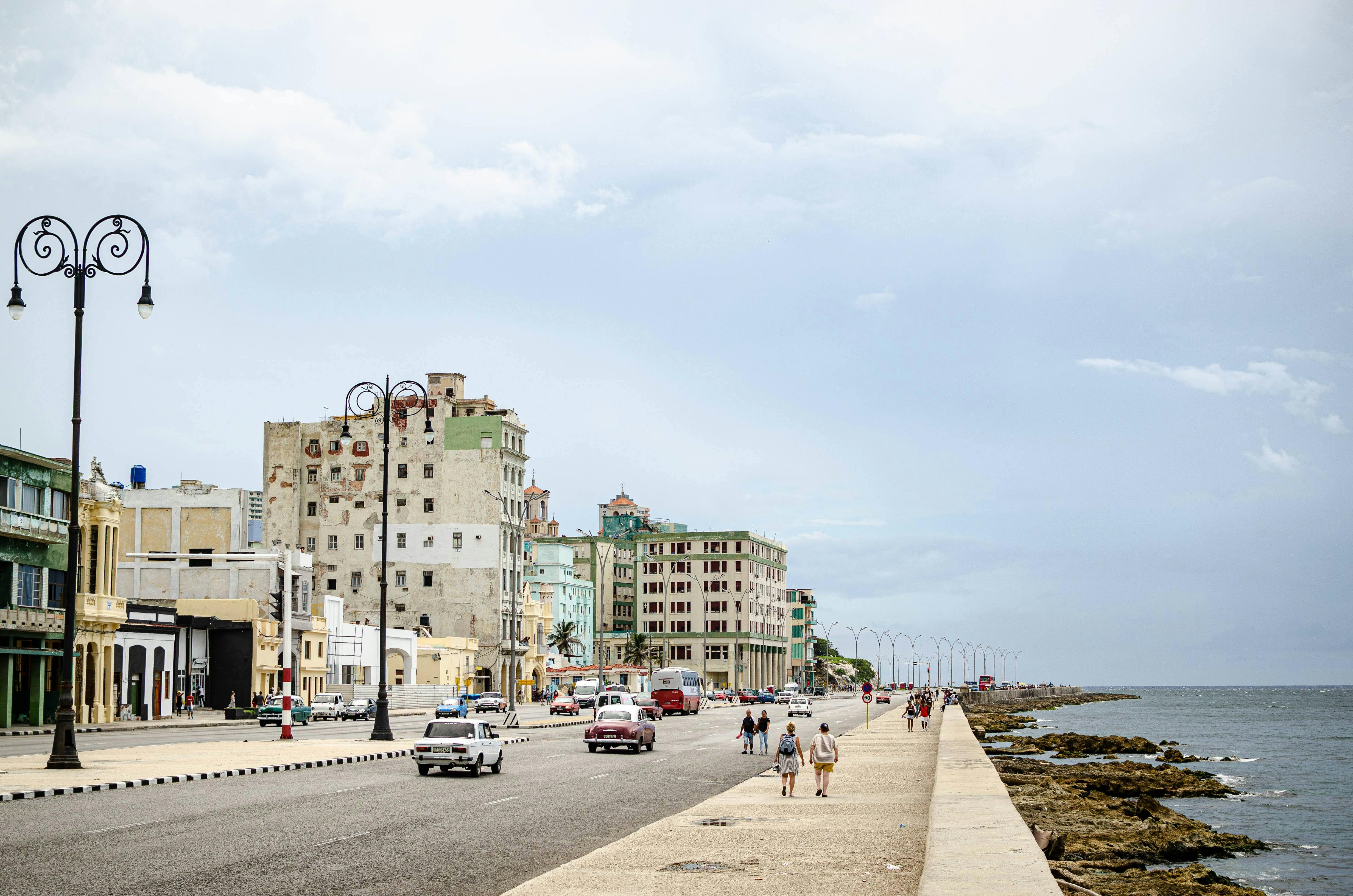 Urban street view of Havana's historic Malecón with classic cars and ocean backdrop.