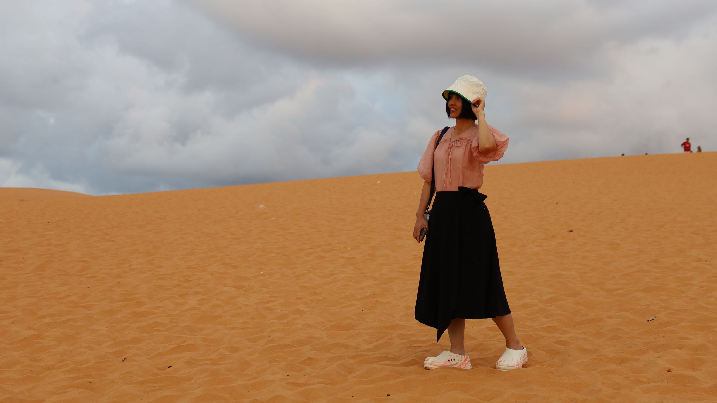 A woman enjoys a cloudy day on the red sand dunes of Phan Thiết, Bình Thuận.