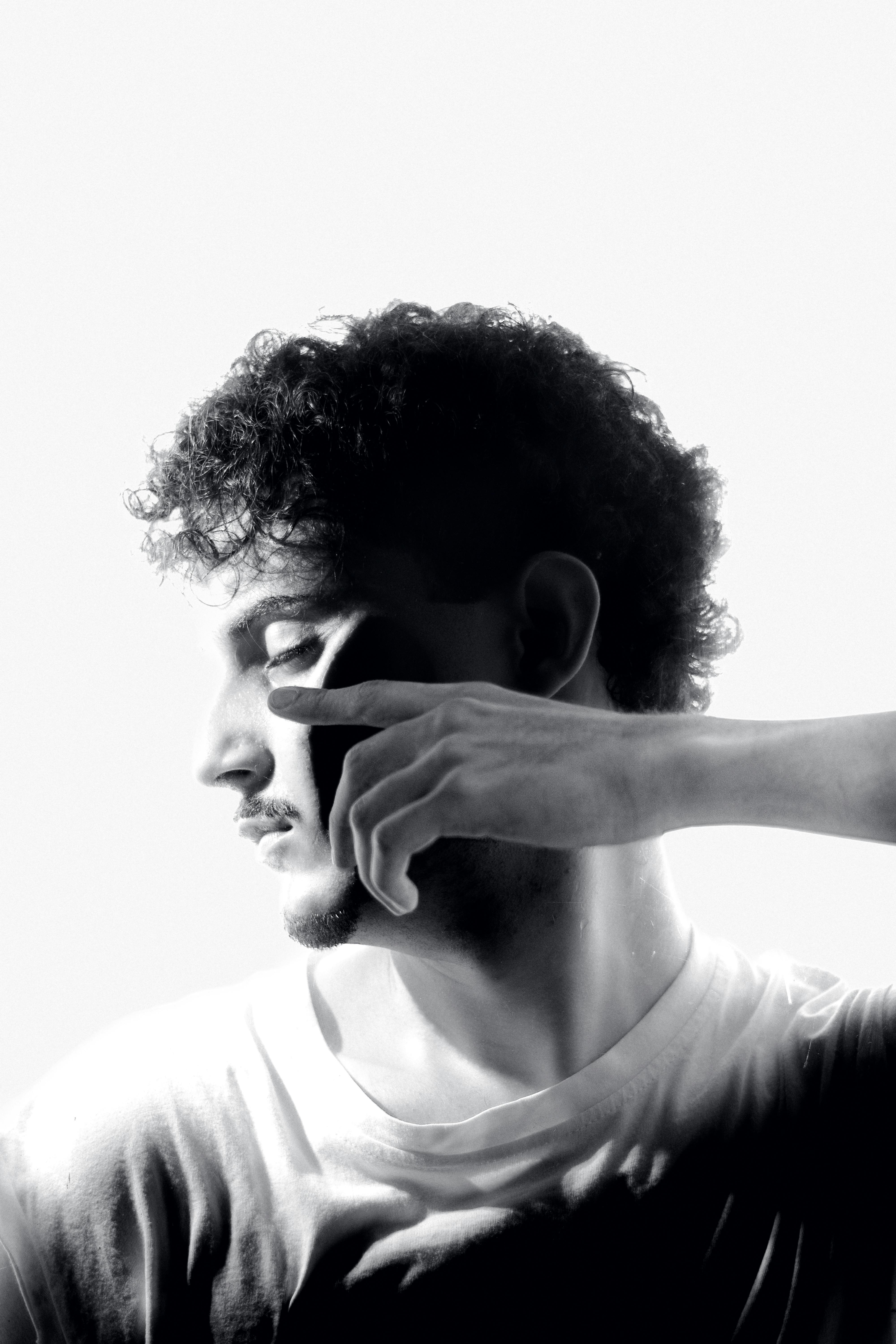 Artistic black and white side profile portrait of a man with shadows and curly hair.