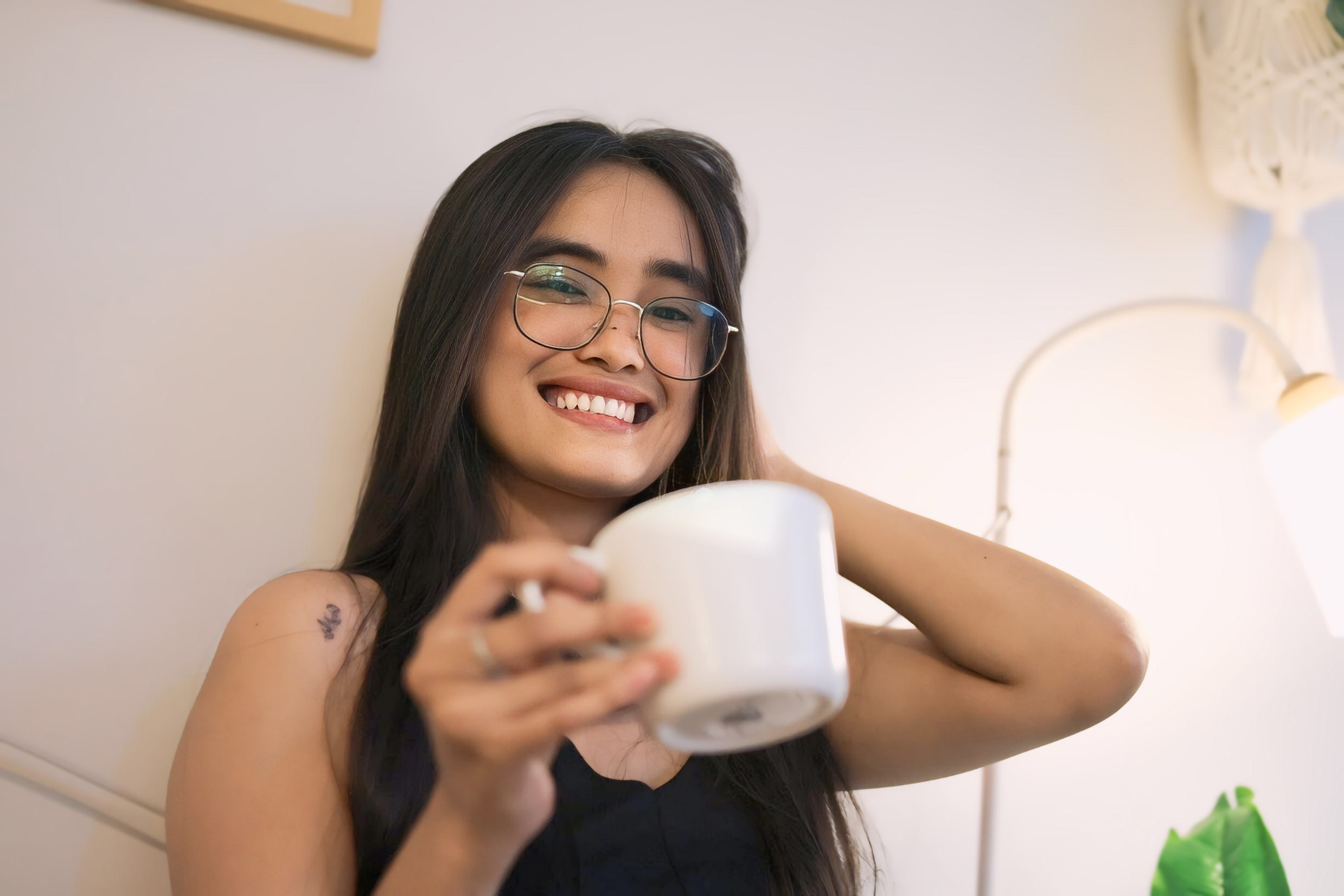 A patient smiling comfortably at home, enjoying a cup of tea, with soft lighting and a blanket, suggesting a relaxed and quick recovery after a procedure. - plastic surgery under local anesthesia