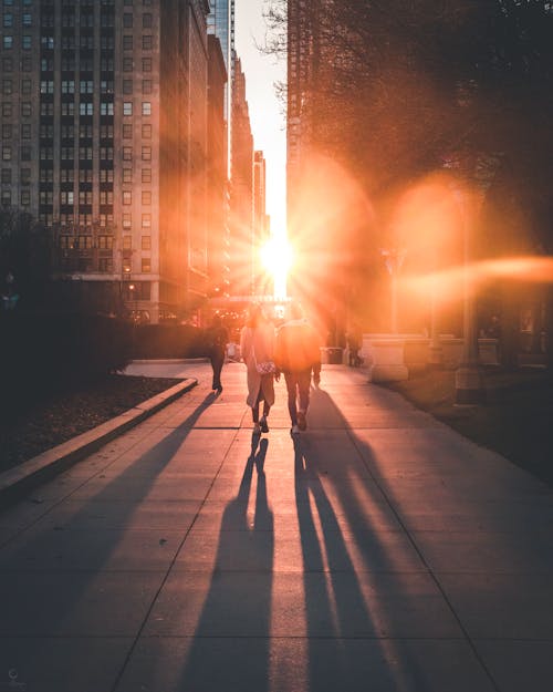 Gente Caminando Por La Calle Con Rayos De Sol Entre Dos Edificios