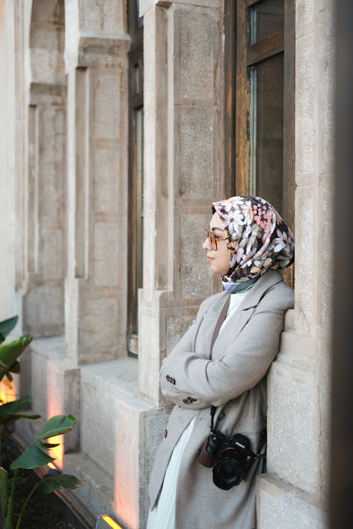 A woman in a hijab leaning against a wall