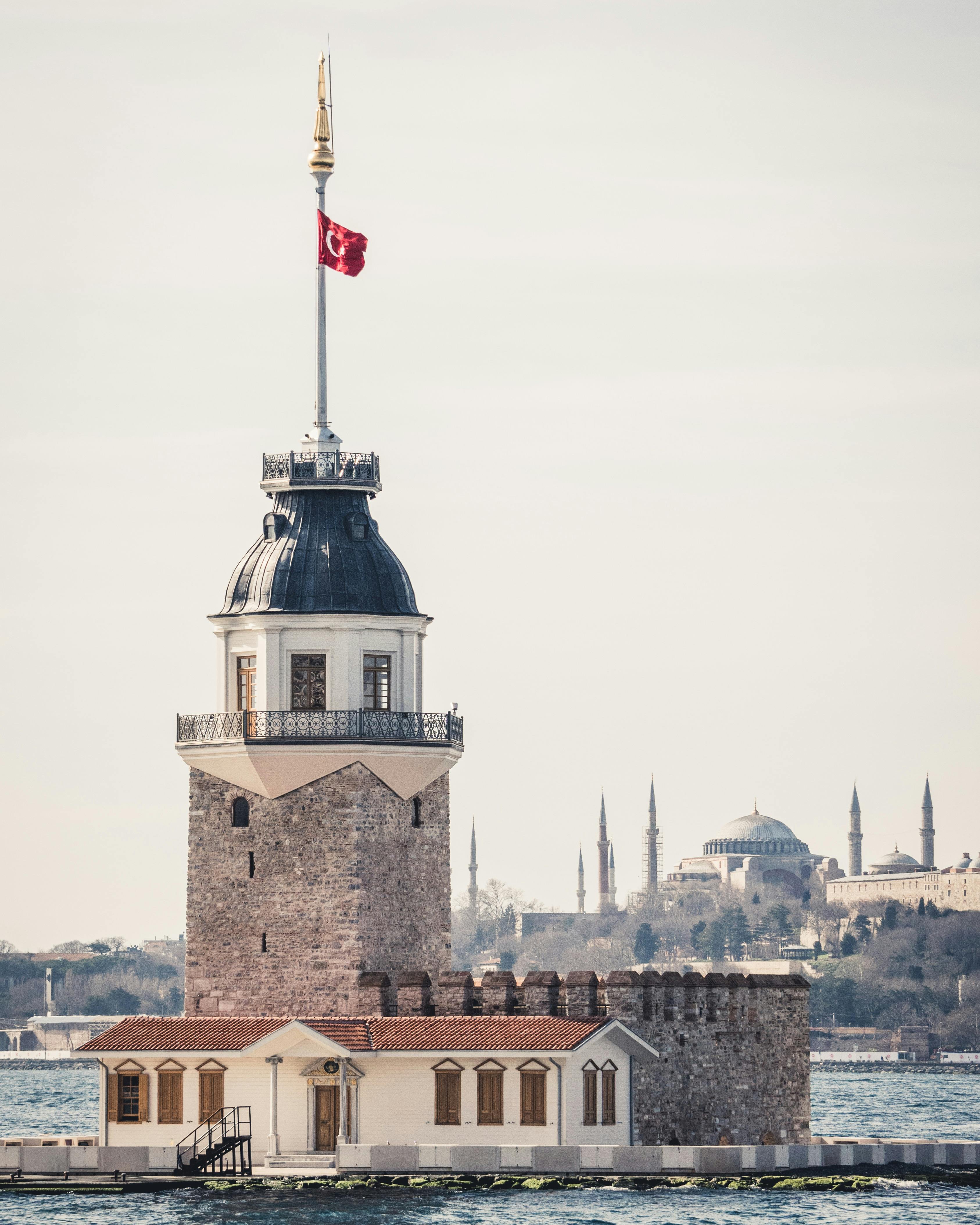View of Maiden's Tower standing on Bosphorus with Istanbul skyline in the background.