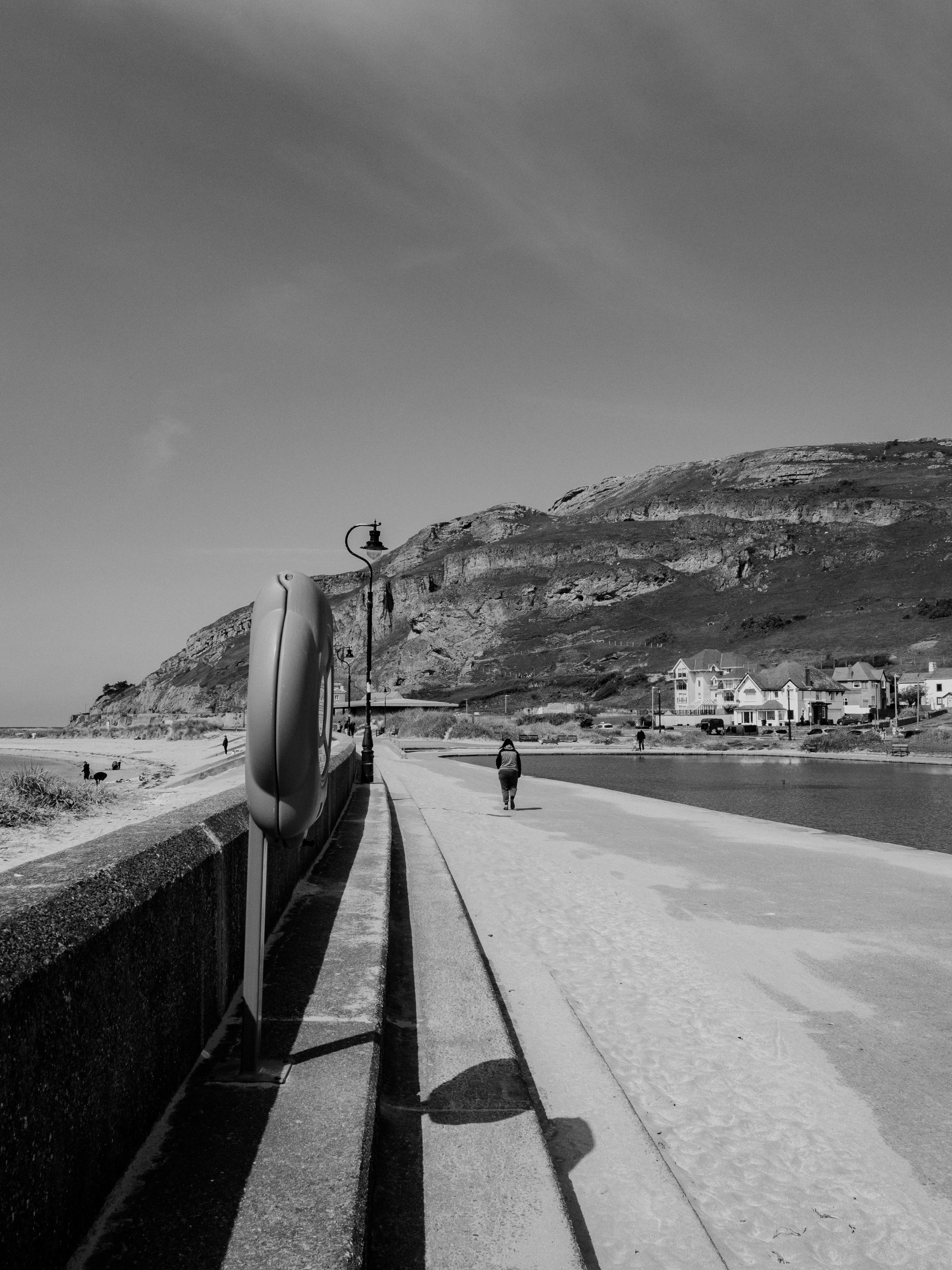 Black and white photo of West Shore Beach in Llandudno, Wales, featuring the coast and hillside.