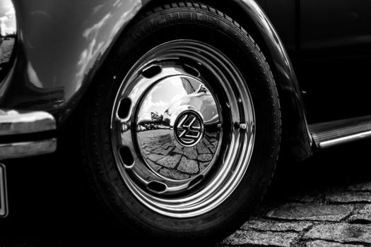 Detailed black and white shot of a classic Volkswagen wheel reflecting Berlin streets.