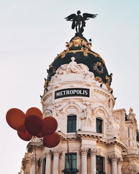 Iconic Metropolis Building in Madrid with floating red balloons. Elegant architecture.