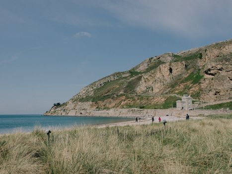 Beautiful view of Llandudno's West Shore Beach with grassy dunes and rocky cliffs in summer.