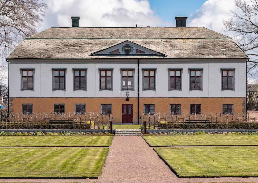 A large building with a green lawn and a white fence