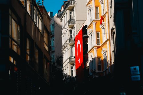 Free A Turkish flag hangs on a vibrant street in an urban setting, showcasing architecture and culture. Stock Photo