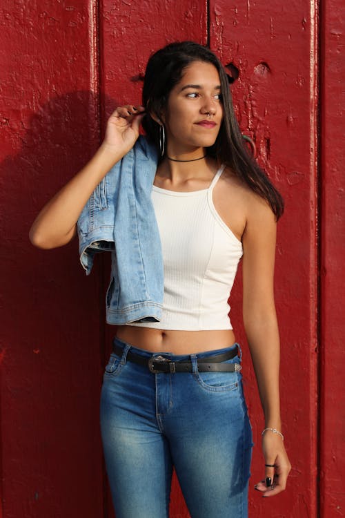 Woman in Tank Top and Blue Denim Jeans With Blue Denim Jacket Slung Right · Free Stock
