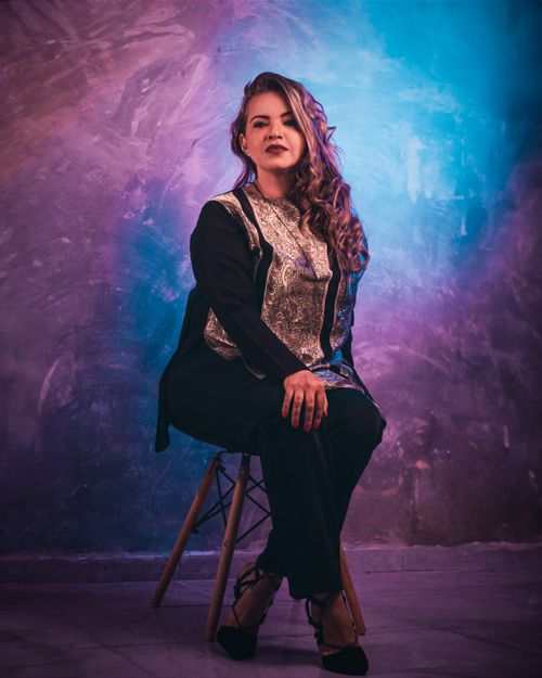 Free Elegant woman in stylish outfit posing in a colorful studio environment, showcasing glamour and confidence. Stock Photo