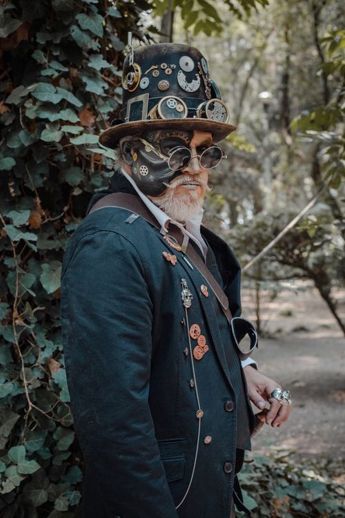 Free Portrait of a man in steampunk attire standing outdoors, surrounded by nature. Stock Photo
