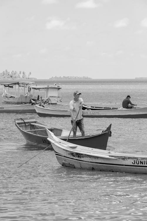 A black and white photo of people in boats