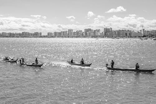 A black and white photo of people in canoes on the water