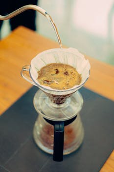 Close-up of hot water being poured over coffee grounds in a dripper for a fresh brew.
