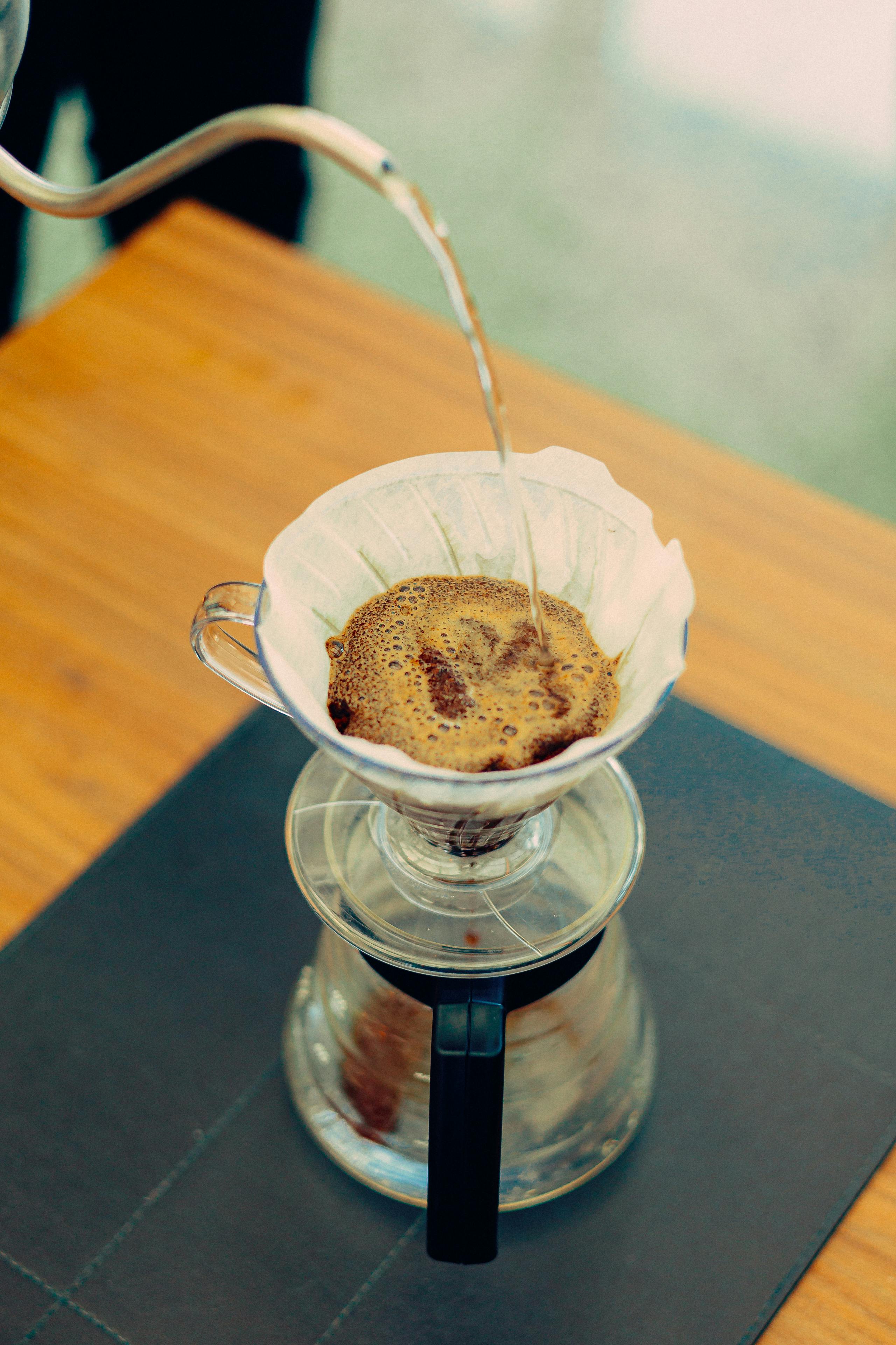 Close-up of hot water being poured over coffee grounds in a drip coffee maker.