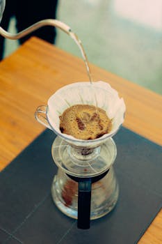 Close-up of hot water being poured over coffee grounds in a drip coffee maker.