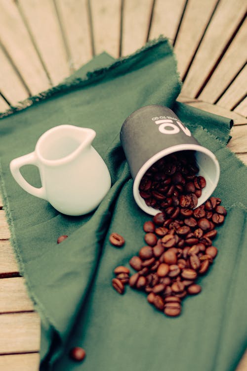 Coffee beans and a cup of coffee on a green cloth