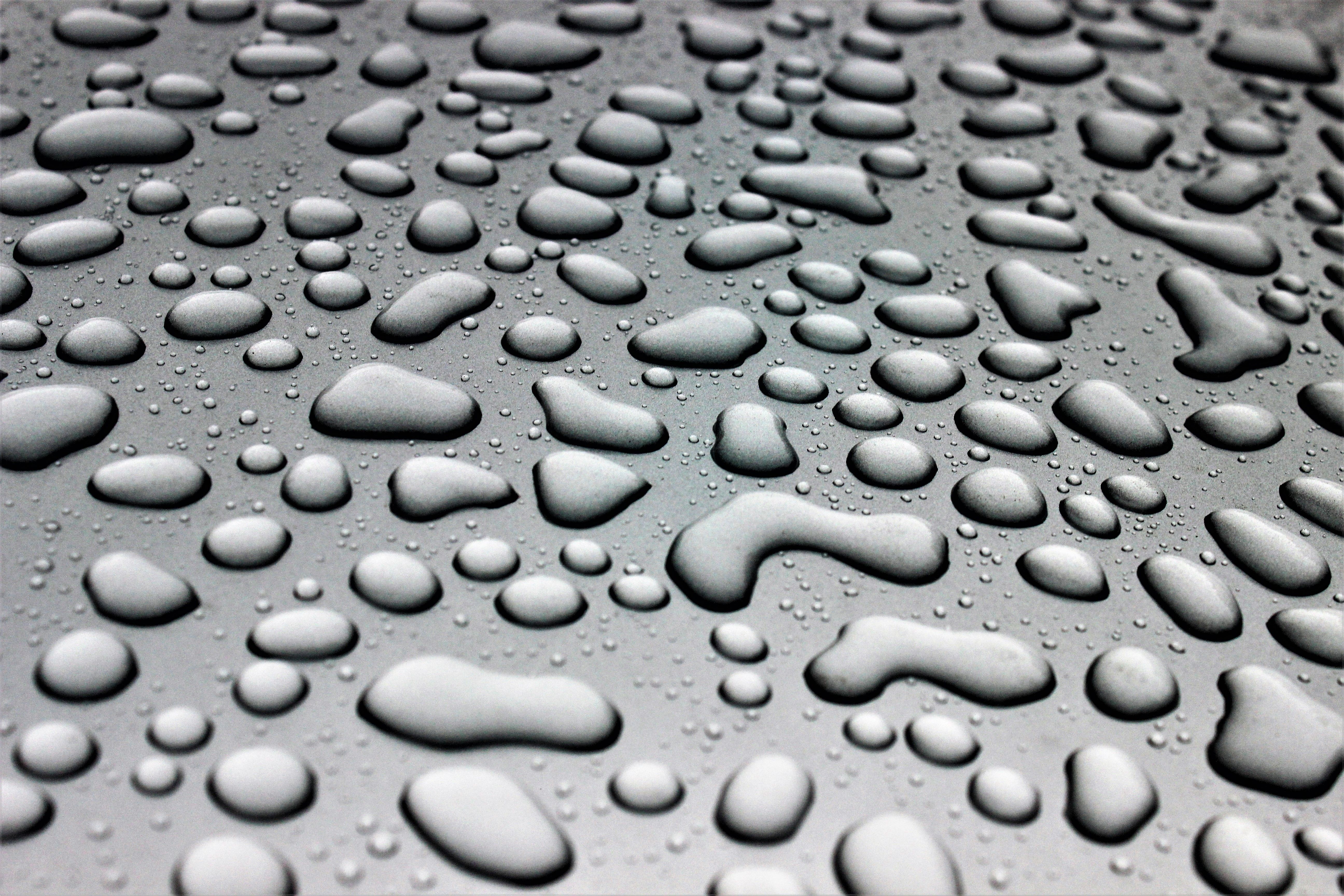 High-quality macro image of water droplets on a black glass pane, creating a textured abstract pattern.. pexels, high, qualit