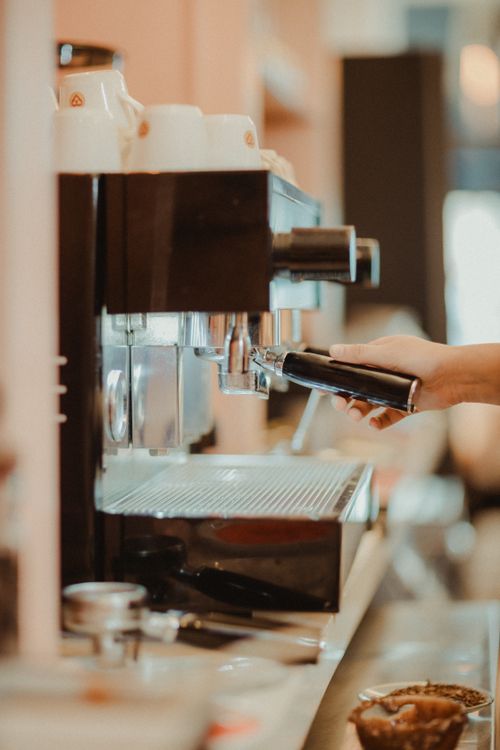 Free A barista's hand using an espresso machine in a coffee shop, focus on the process. Stock Photo