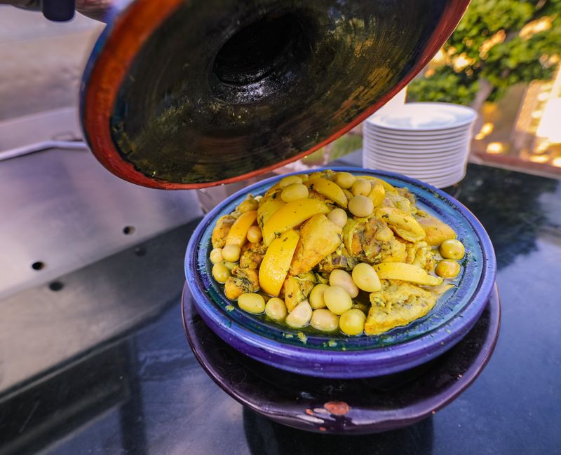 A Moroccan chef preparing traditional tagine with fresh ingredients and spices.